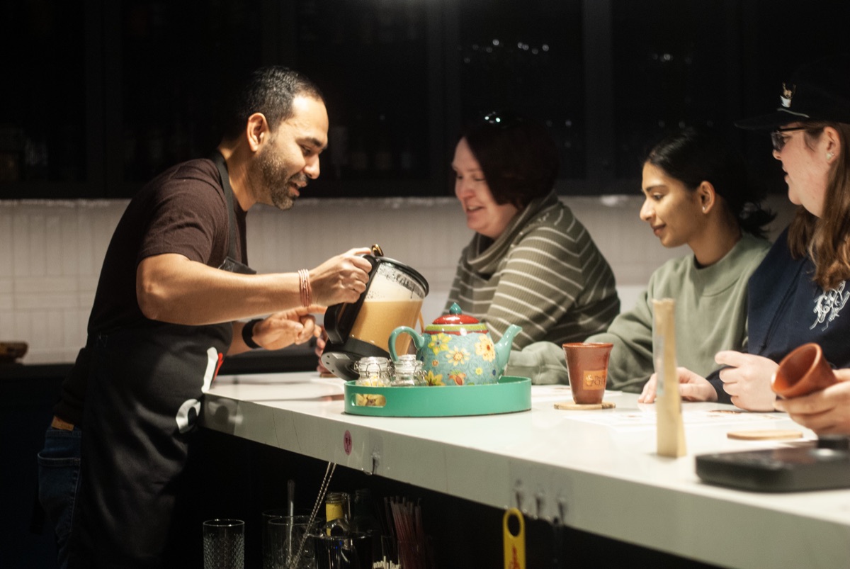 Rajiv Roy pouring chai for customers at a counter